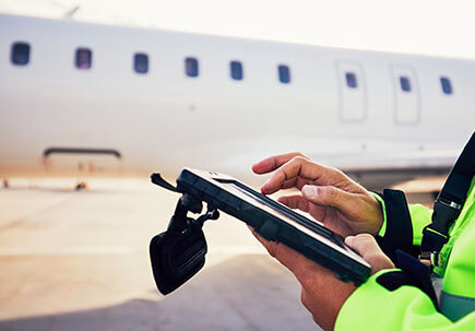 Workman using a tablet on an airfield Workman using a tablet on an airfield